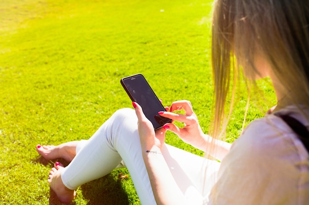 Look from behind woman's shoulder with smartphone in her tender arms