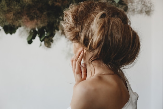 Look from behind at woman with blonde hair made up on her head