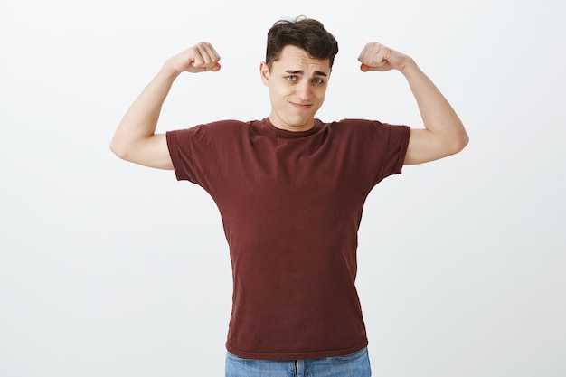 Look how strong I am. Portrait of self-assured handsome european guy in red t-shirt