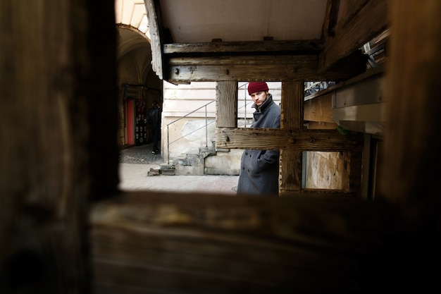 Look through wooden blocks at young man in grey coat 