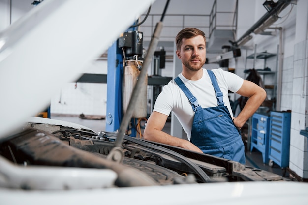 Looking at the camera. Employee in the blue colored uniform works in the automobile salon