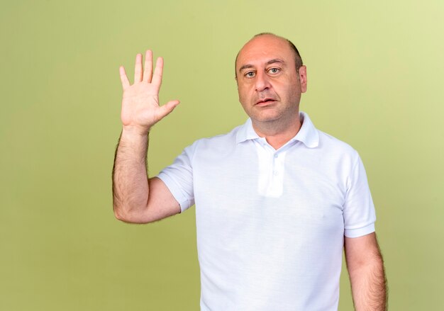 Looking at camera mature man showing five isolated on olive green background