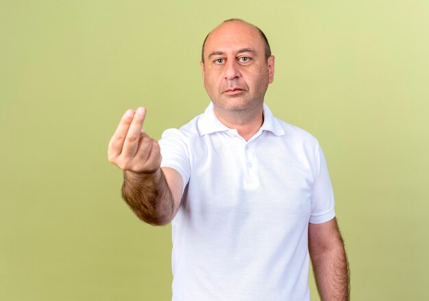 Looking at camera mature man showing tip gesture isolated on olive green background