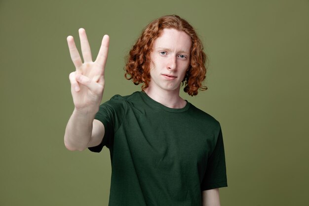 Looking at camera showing three young handsome guy wearing green t shirt isolated on green background