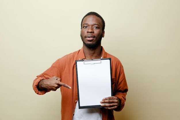 Guardando la fotocamera giovane azienda maschio afroamericano e punti negli appunti isolati su sfondo bianco