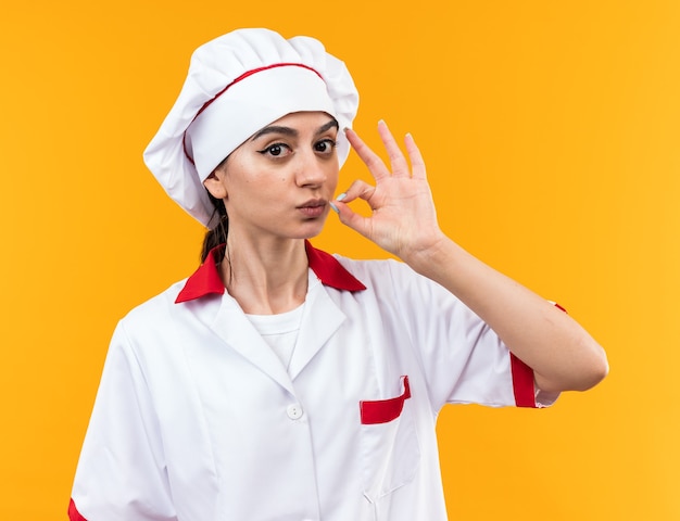 Foto gratuita guardando la telecamera giovane bella ragazza in uniforme da chef che mostra un gesto delizioso