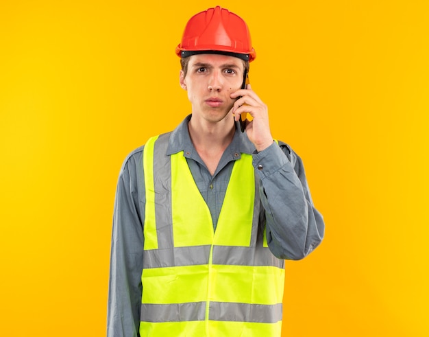 Free photo looking at camera young builder man in uniform speaks on phone