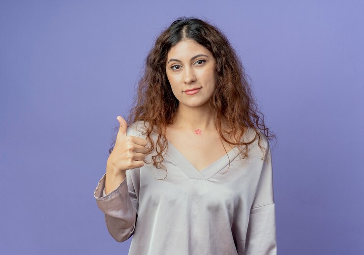 मुफ़्त फोटो looking at camera young pretty girl her thumb up isolated on blue background