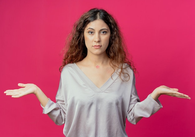 Free photo looking at camera young pretty girl spreads hands isolated on pink background