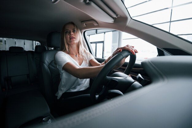 鏡を見る。サロンで現代の車の女の子。昼間の屋内。新しい車を買う