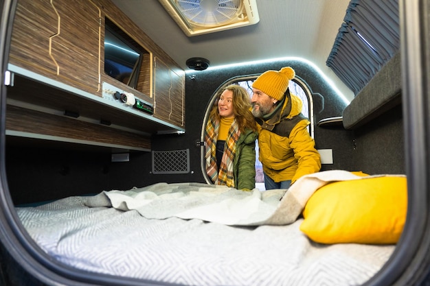 Looking news on tv mature couple in camper traveling Man hold woman happy pleasant smiling enjoying time together Middle aged couple having fun on winter vacation Travel love concept