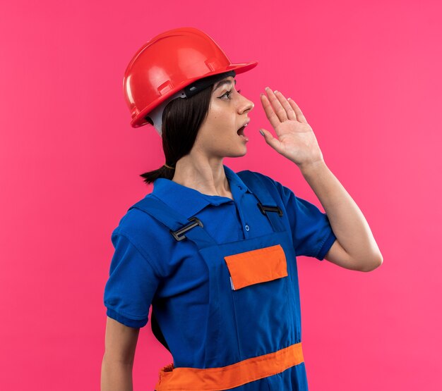 誰かを呼んでいる制服を着た若いビルダーの女性の側を見て
