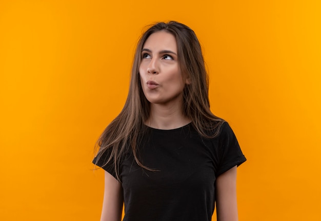Free photo looking at side young caucasian girl wearing black t-shirt showing kiss gesture on isolated orange background