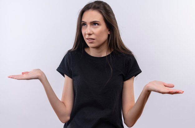 Looking at side young caucasian girl wearing black t-shirt spreads hands on isolated white background