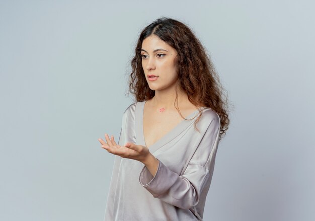 Looking at side young pretty female office worker holding out hand to side isolated on white background