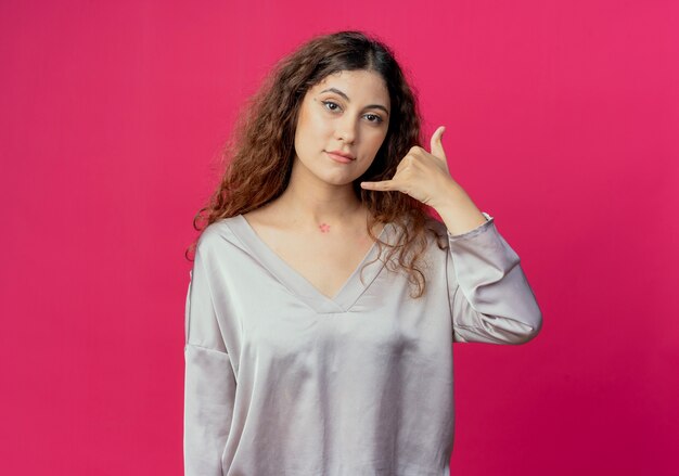 Looking at side young pretty girl showing phone call gesture isolated on pink background