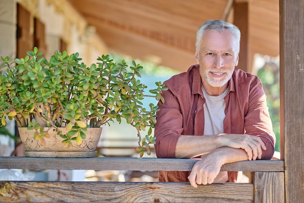 Looking thoughtful. Mature gray-haired man standing with a thoughtful look