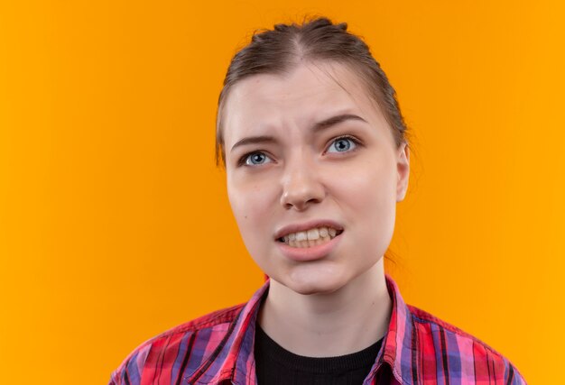 Looking at up concerned young beautiful girl wearing red shirt on isolated yellow background