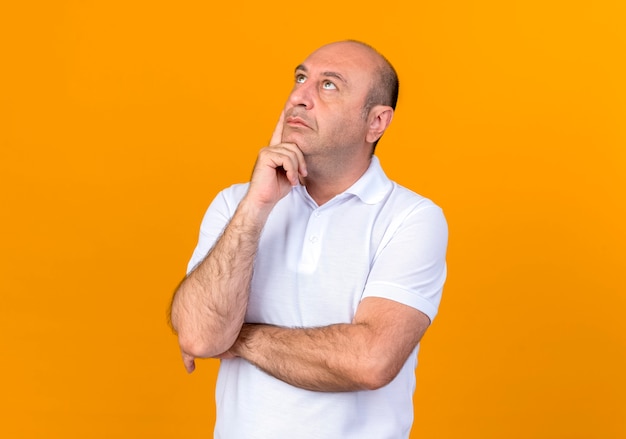 Looking at up thinking casual mature man putting hand on chin 