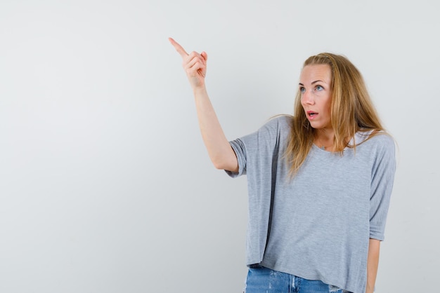 The looking up woman is pointing up with forefinger on white background