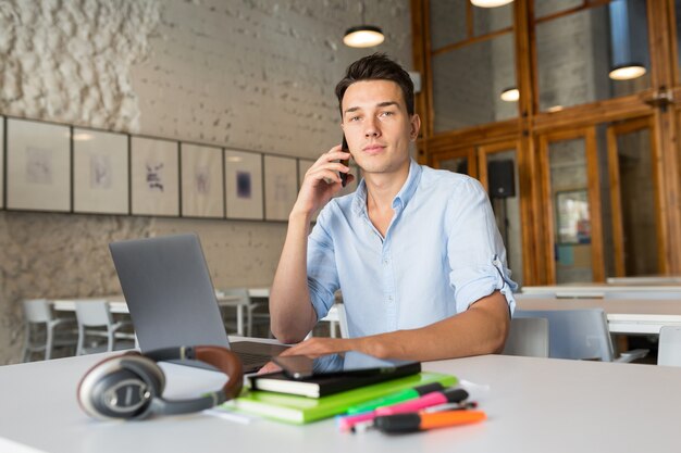 Looking young handsome man sitting in co-working office