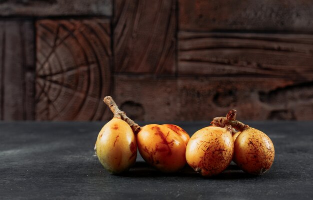 Loquats side view on a dark textured and wooden background space for text