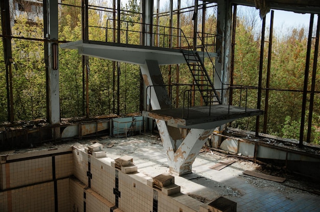 放射性ゴーストタウンのチェルノブイリ市ゾーンにあるスイミングプール付きの失われた学校のスポーツジム