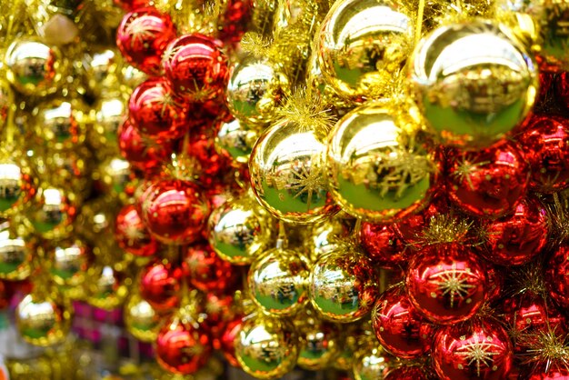 A lot of Christmas glass red and yellow balls are hanging in the store. Festive new year decor