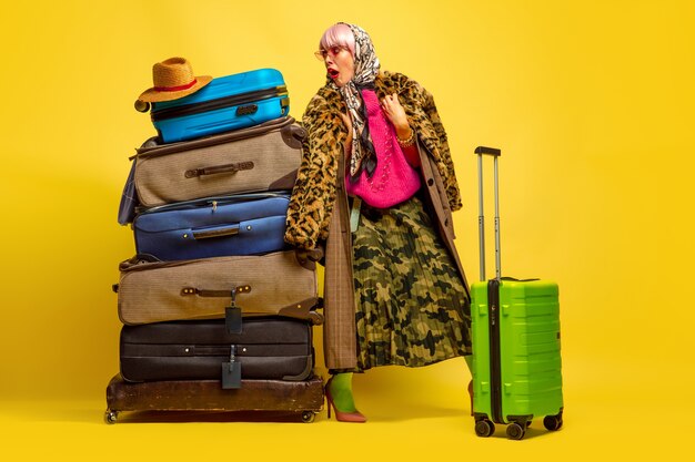 Много одежды для путешествий. Портрет кавказской женщины на желтом пространстве