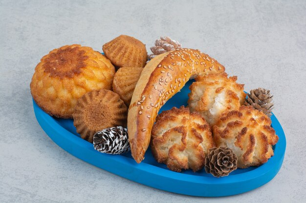 A lot of fresh delicious cookies with small pinecones on blue plate.