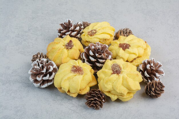 A lot of fresh delicious cookies with small pinecones on white table.