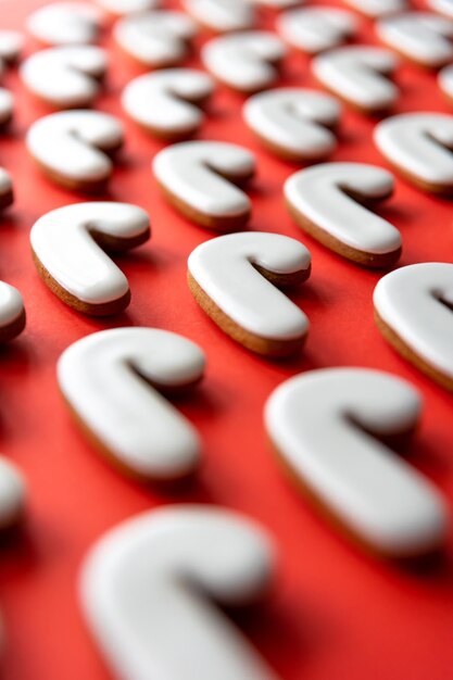 A lot of gingerbread candy cane shaped cookies on a red background