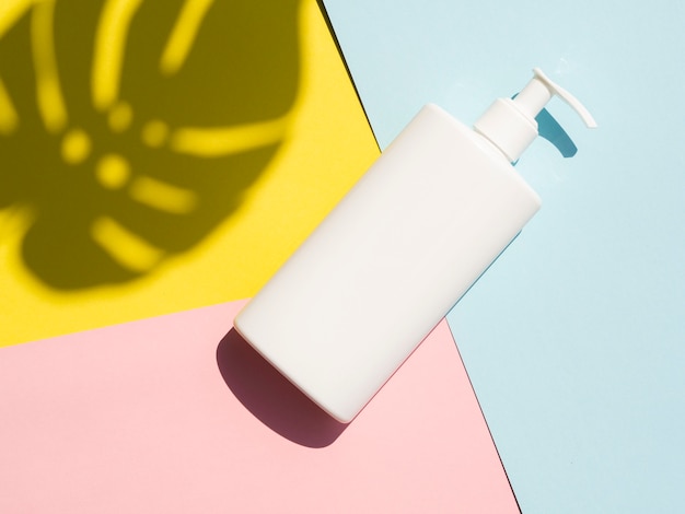 Free photo lotion bottle mock-up next to monstera leaf shadow