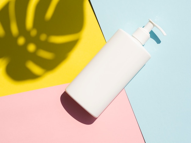 Lotion bottle mock-up next to monstera leaf shadow