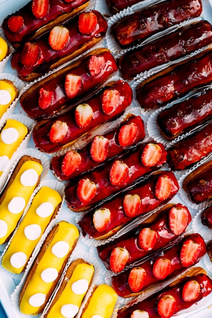 Lots of eclairs with chocolate and fruits topping