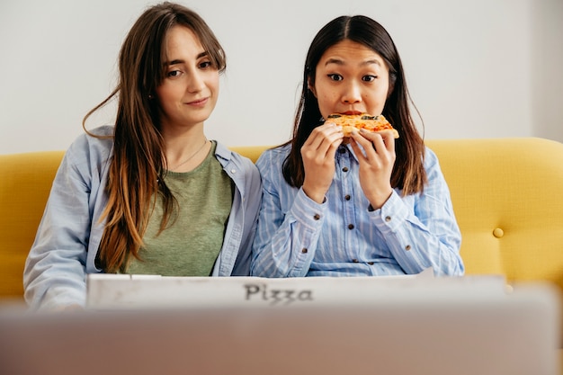 Lounging women eating pizza with movie