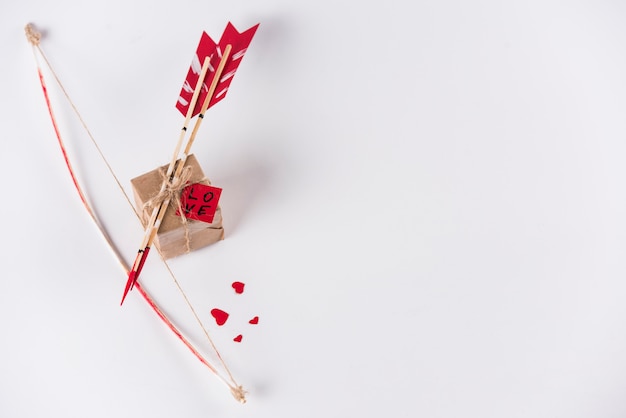 Love arrows with bow and gift box on white table