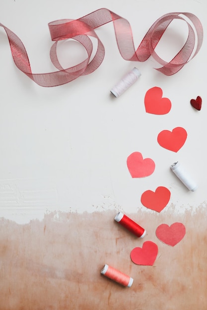 Любовный фон с бумажными сердечками и красной лентой на белом фоне Premium Фотографии