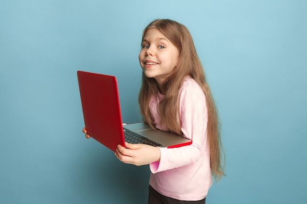 The love of the computer. Teen girl with notebook on a blue background. Facial expressions and people emotions concept