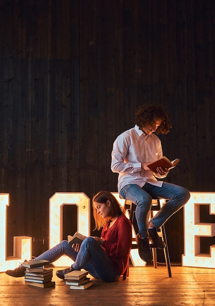 教育への愛。イルミネーションでボリュームのある文字で飾られた部屋で一緒に読んでいる若い学生のカップル。