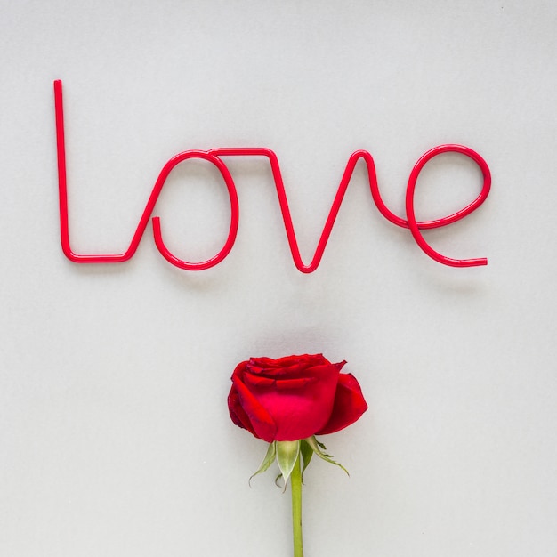 Free photo love inscription with red rose on table