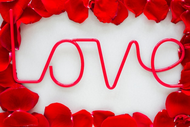 Love inscription with rose petals on grey table