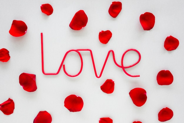 Love inscription with rose petals on table 