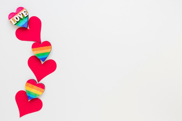 Iscrizione di amore con piccoli cuori rossi di carta e arcobaleno