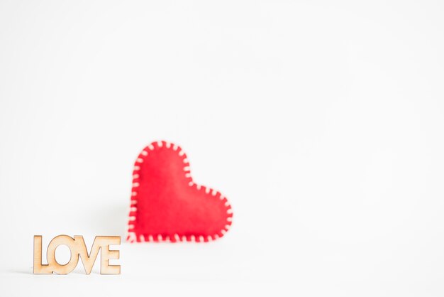 Love inscription with small toy heart on table