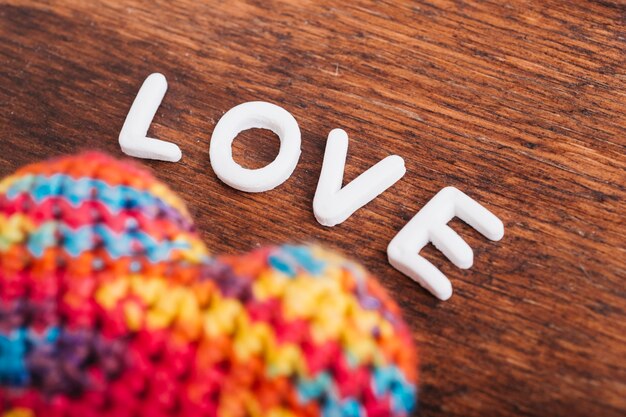 Free photo love inscription with soft heart on wooden table