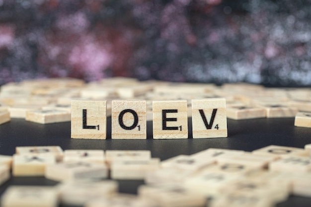 Символическое письмо любви или loev черными буквами на деревянных кубиках горизонтально. Фото высокого качества