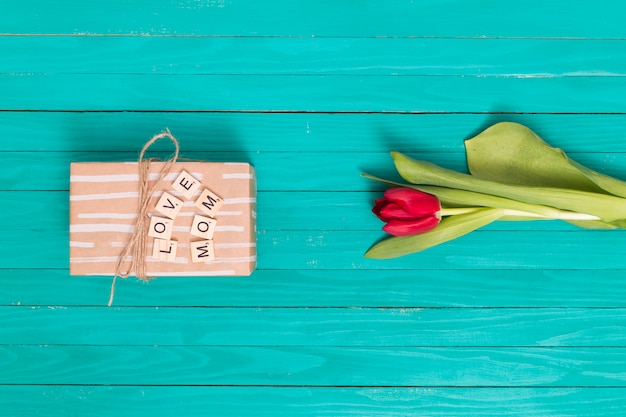 Love; mom; text on wooden block with gift box and tulip flower