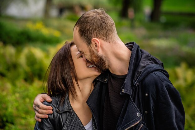 秋の公園のラブシーン-あごひげを生やした男性が頭の中でかわいい幸せな女性にキスします。