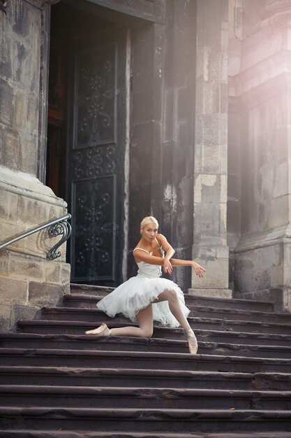 彼女のダンスを見るのが大好きです。古い建物の階段に立っている彼女の膝の上にポーズをとっているバレリーナのソフトフォーカスショット